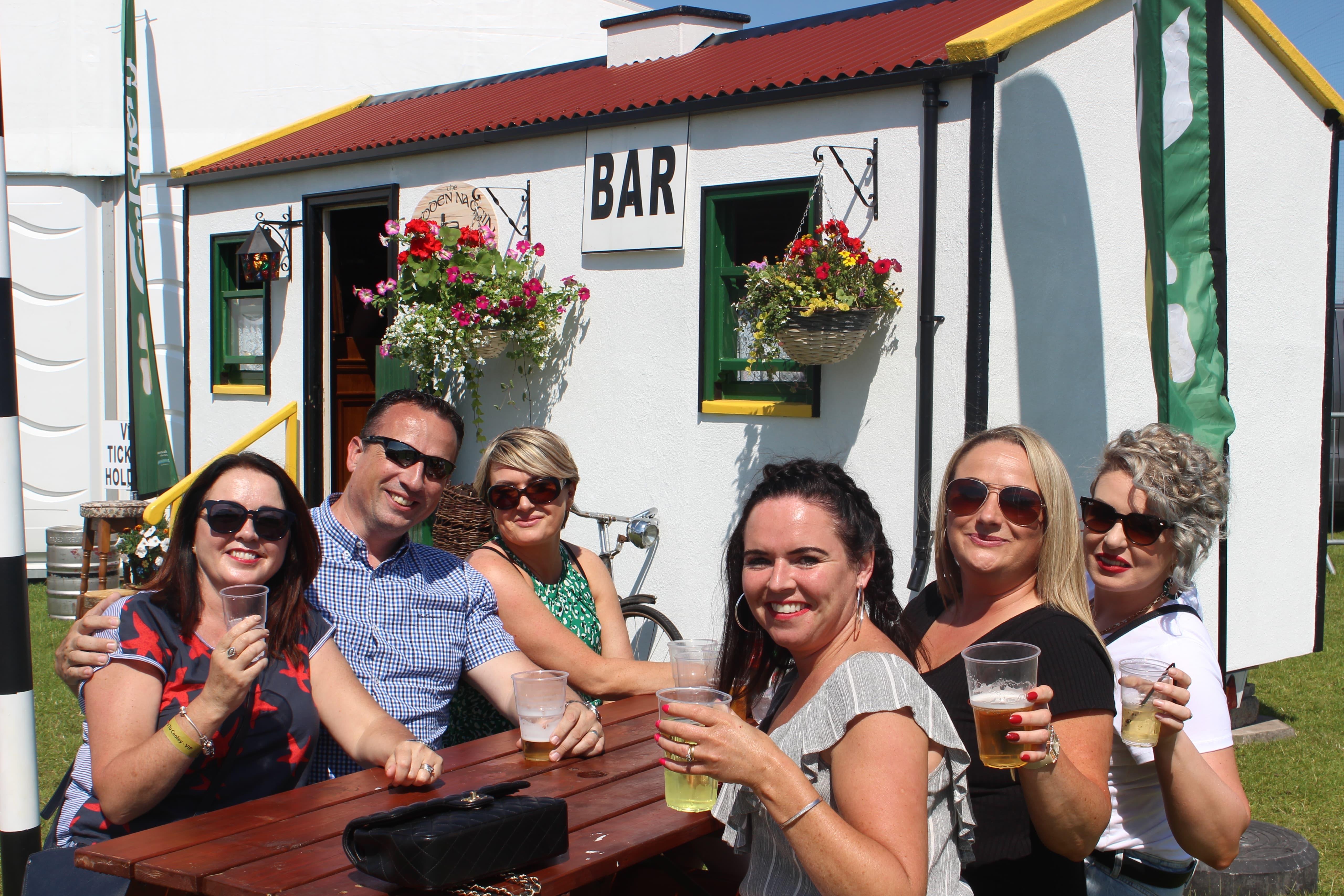 Group seated outside The Hidden Naggin with bar in the background